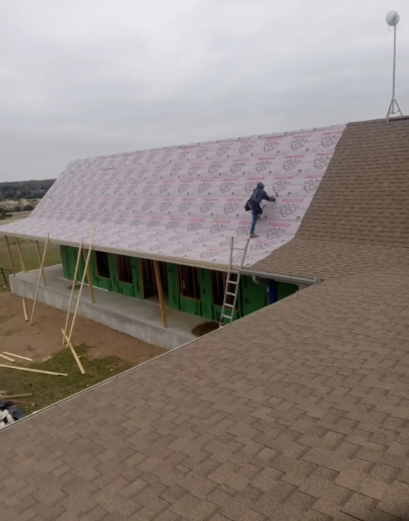 Worker preparing underlayment for a metal roof installation in Allen